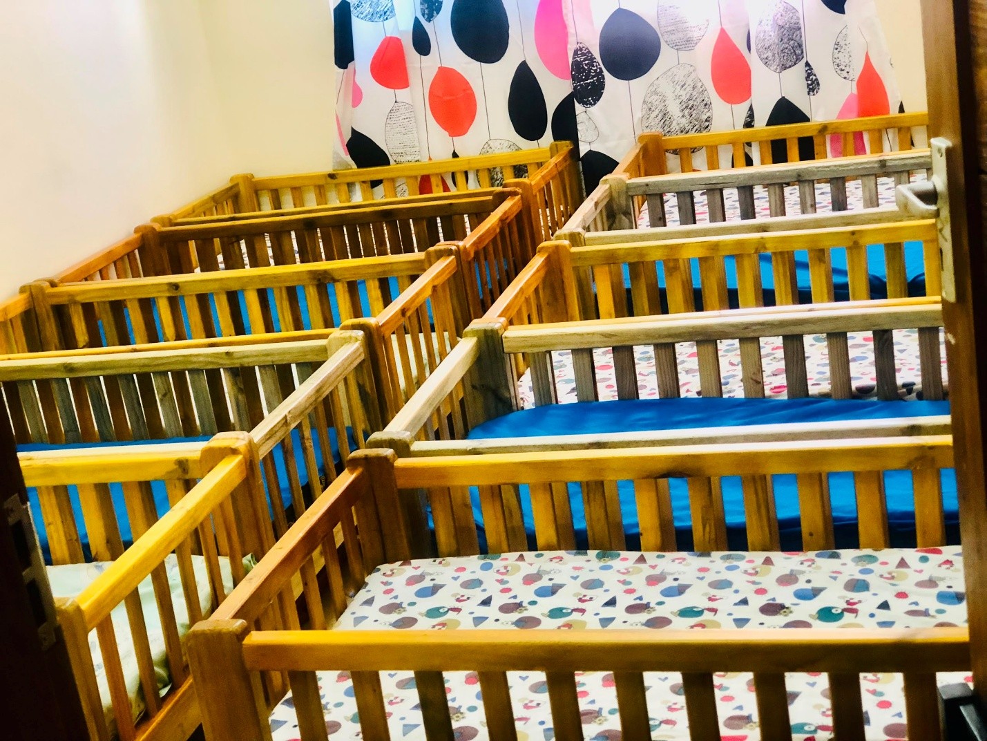 Labelled wooden cots in the safe-sleep room